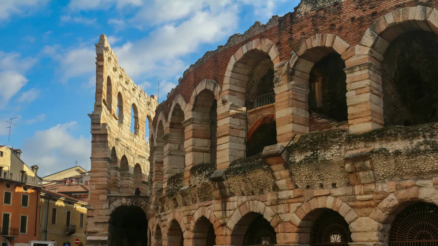L'Arena di Verona: gli archi in pietra dell'anfiteatro romano e l'«Ala», sotto un cielo di nuvole bianche